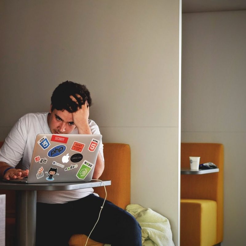 man looking frustrated whilst working on laptop